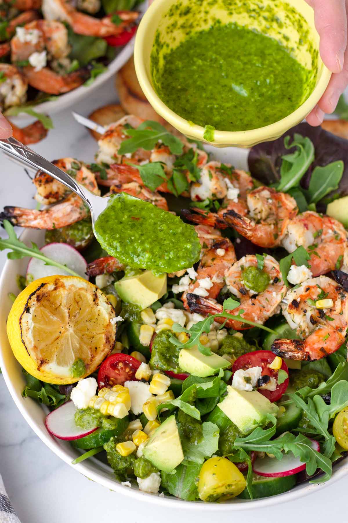 spooning basil vinaigrette onto shrimp salad
