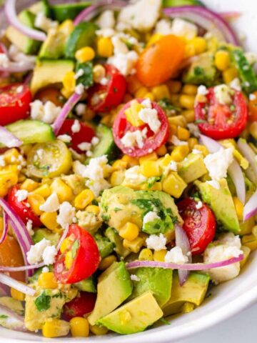 bowl of avocado corn salad with tomatoes and feta