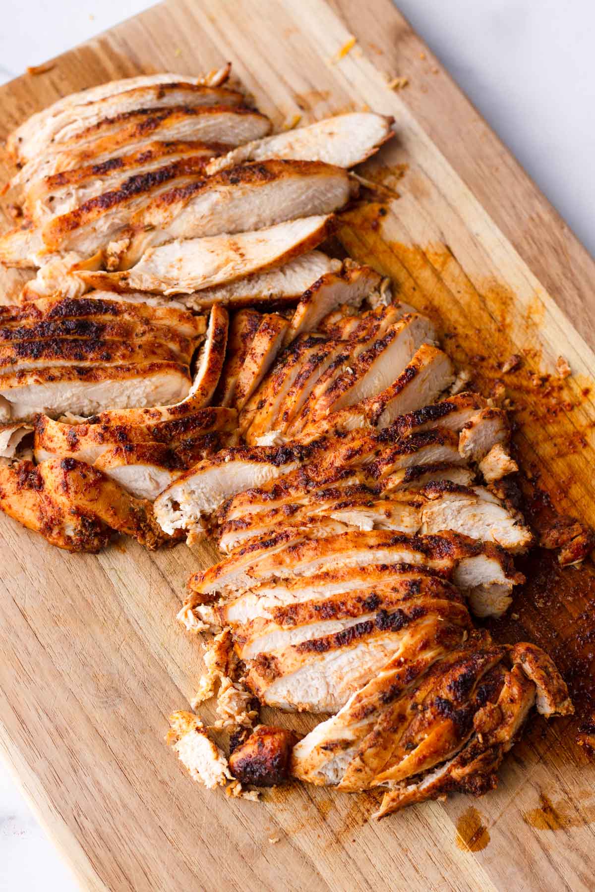 sliced cooed chicken breasts on cutting board
