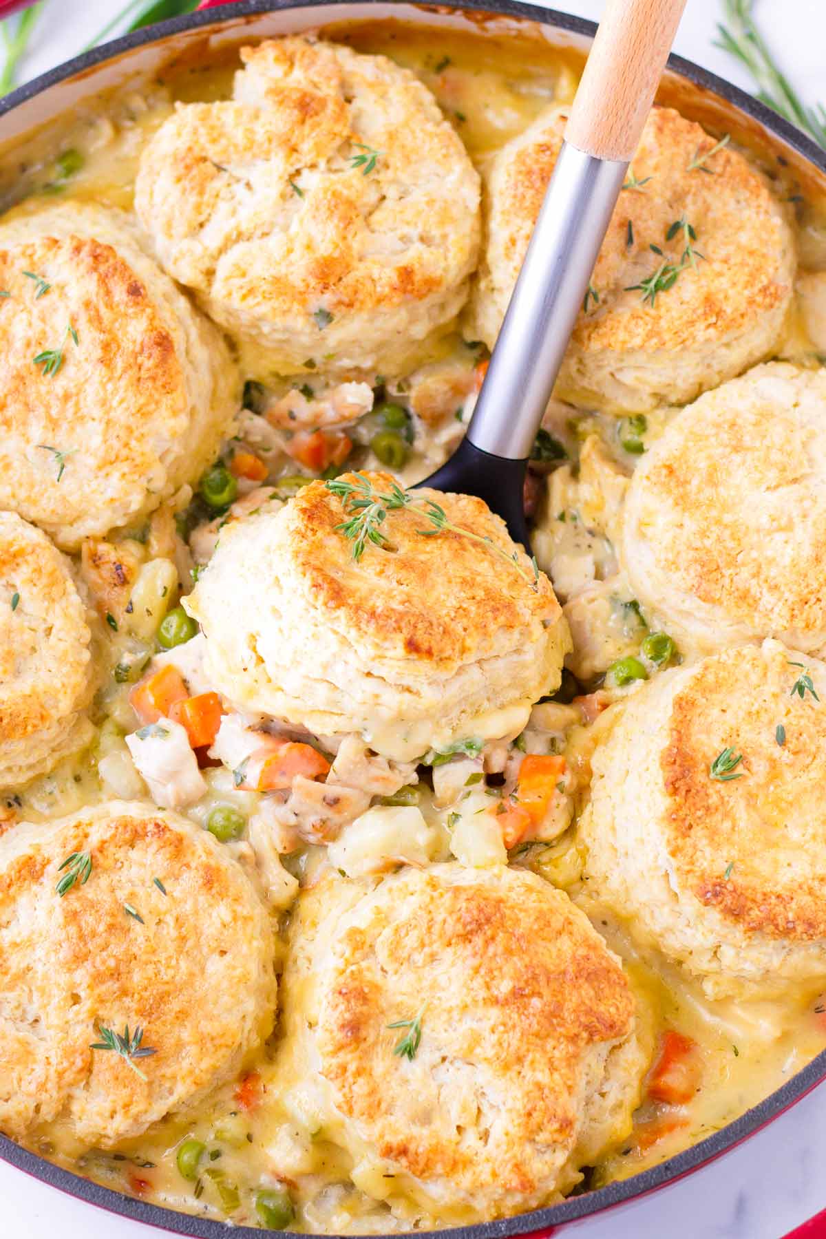 scooping a serving of chicken pot pie with a biscuit