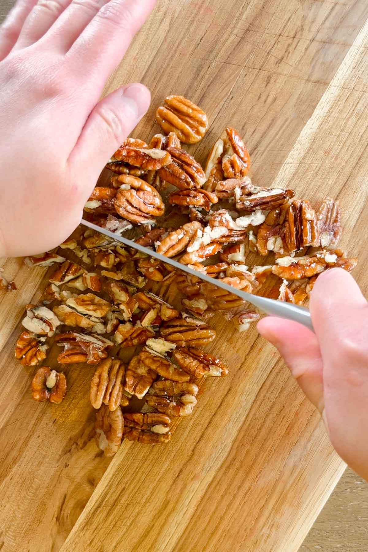 chopping caramelized pecans on cutting board