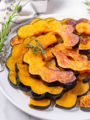 maple roasted acorn squash slices stacked on plate