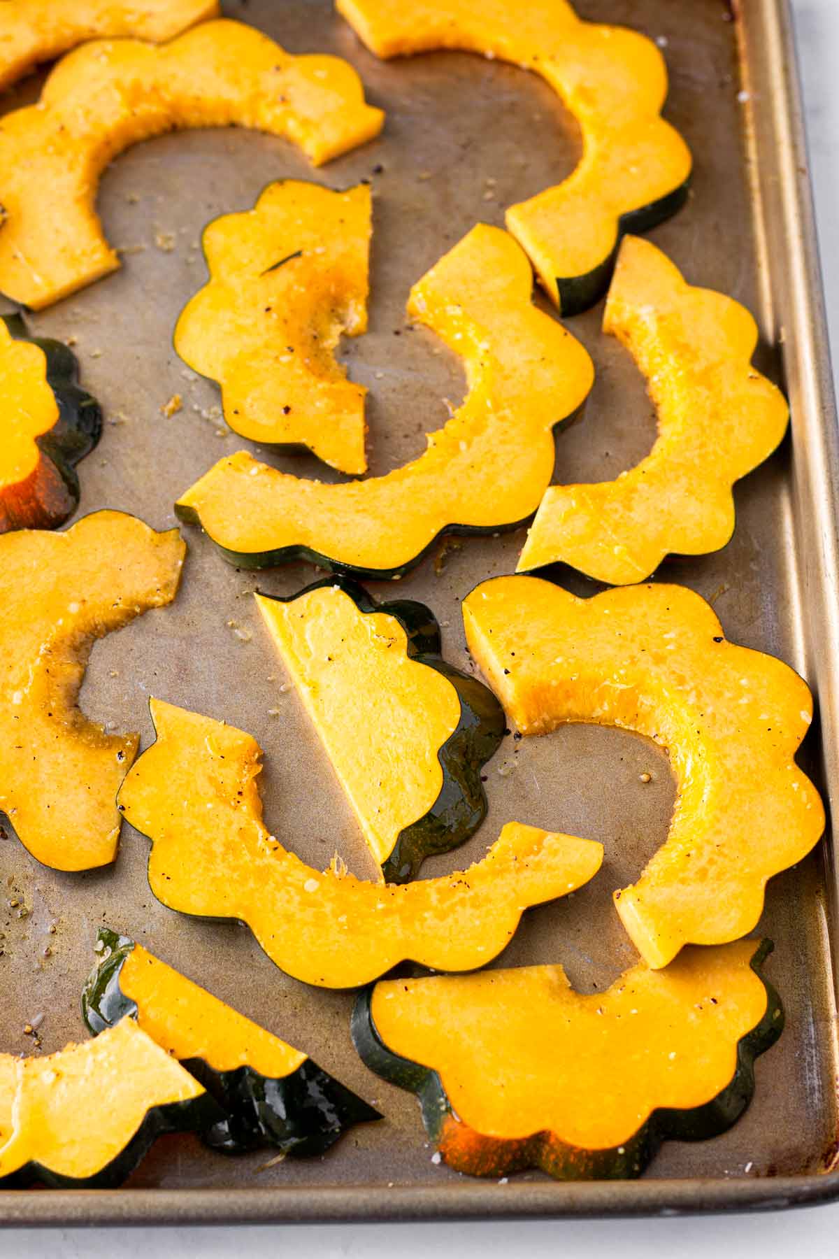 seasoned uncooked squash slices on a sheet pa