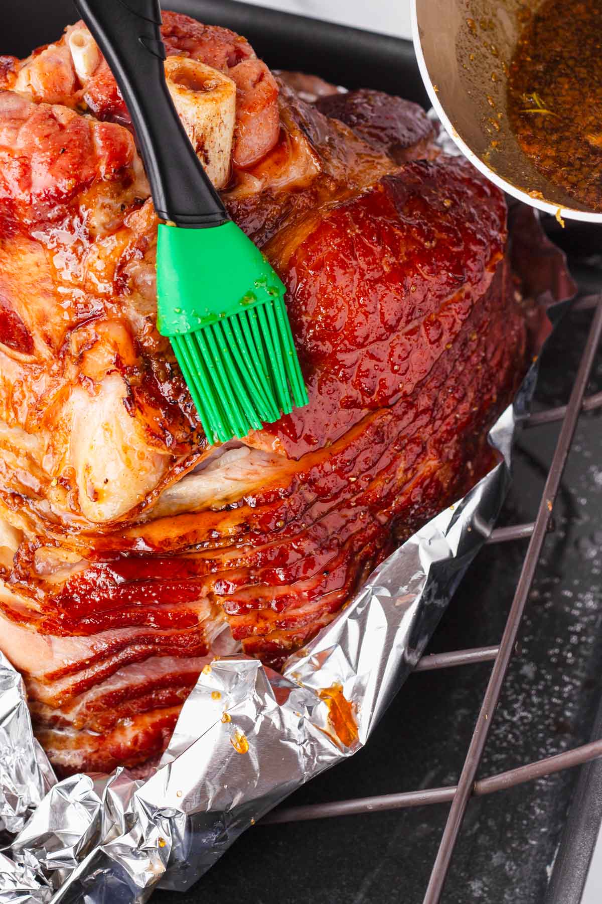 brushing a cooked ham with glaze