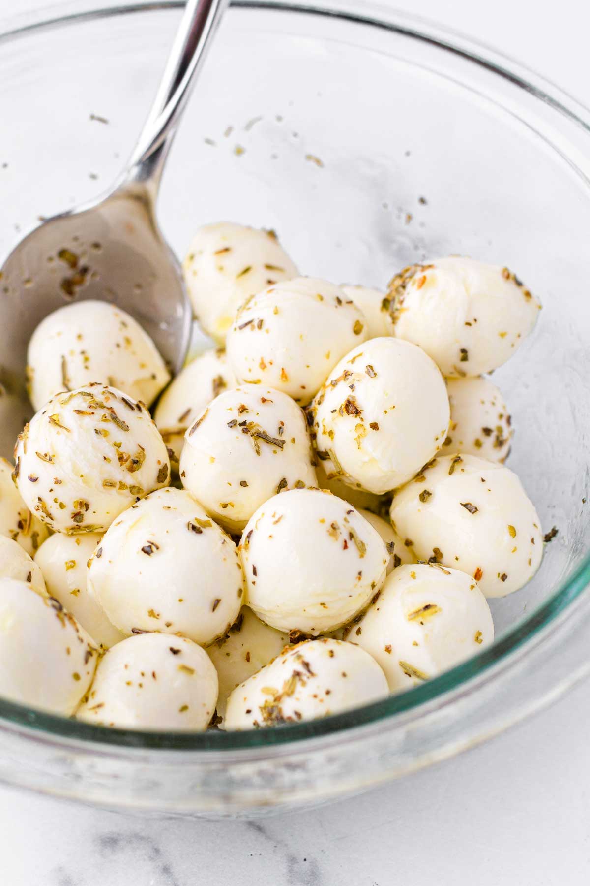 tossing mozzarella balls with olive oil and italian seasoning