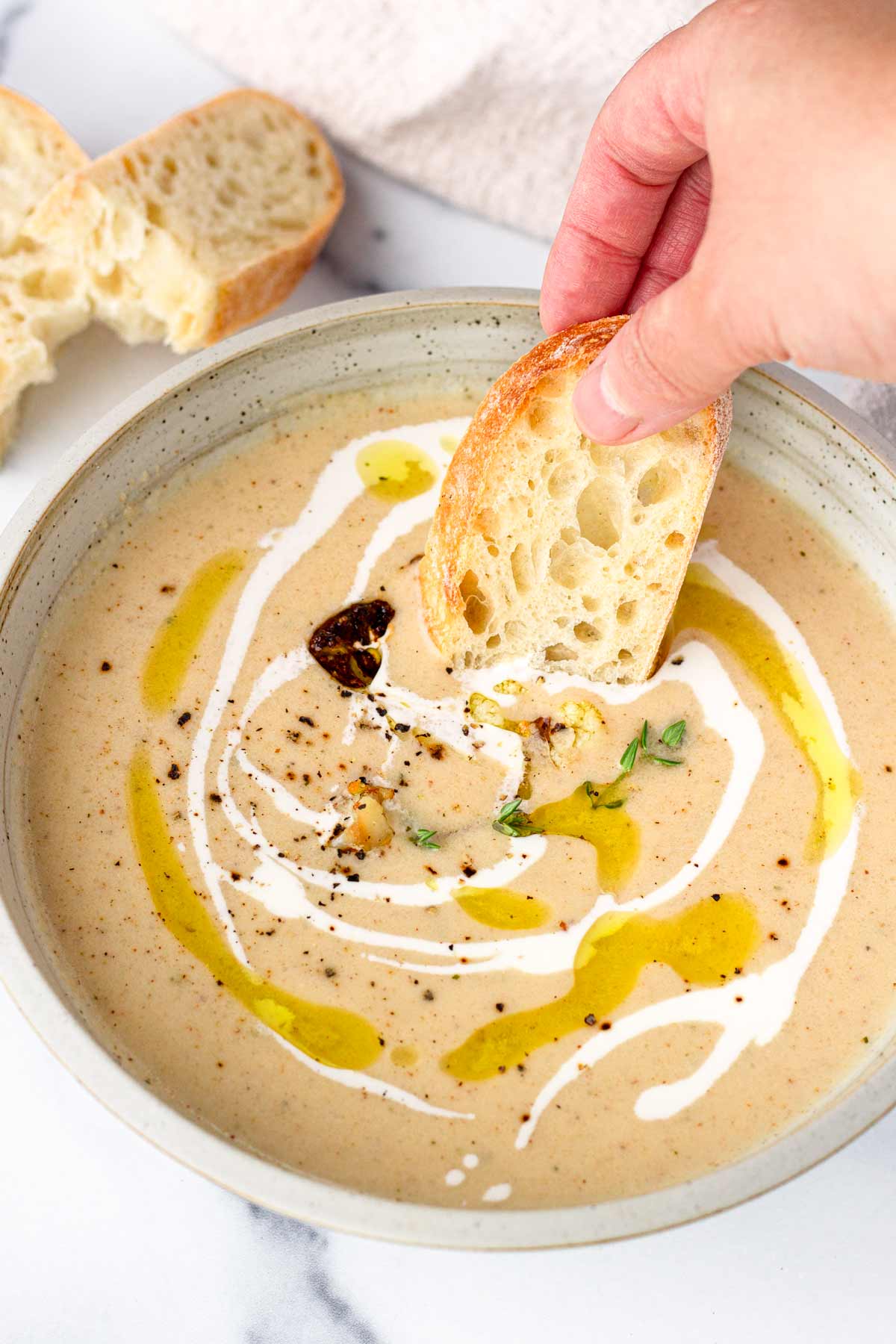 dipping toast into bowl of cauliflower soup