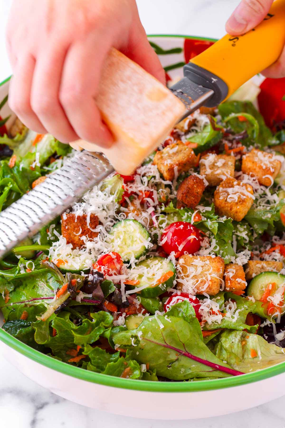 grating cheese on top of prepared salad