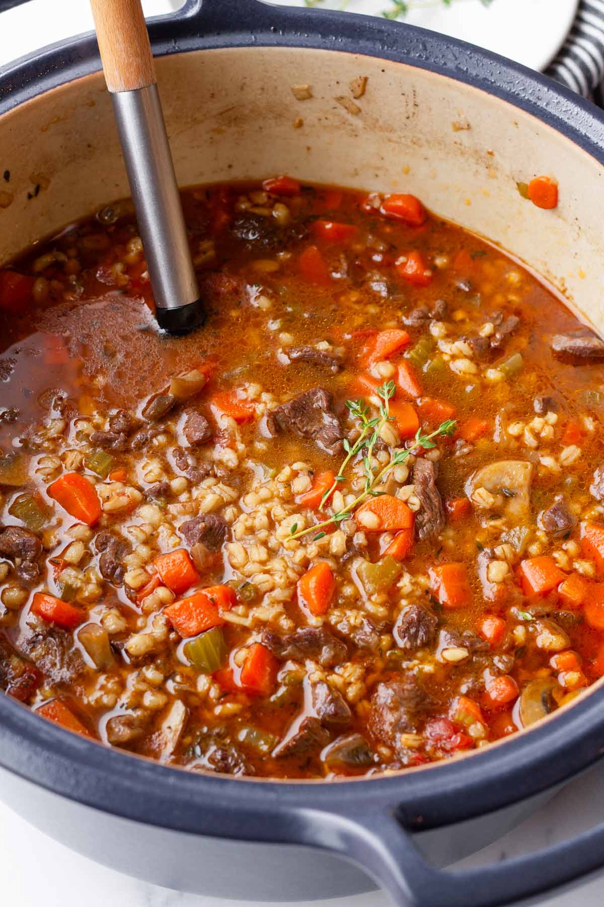 one pot beef barley soup in a blue dutch oven