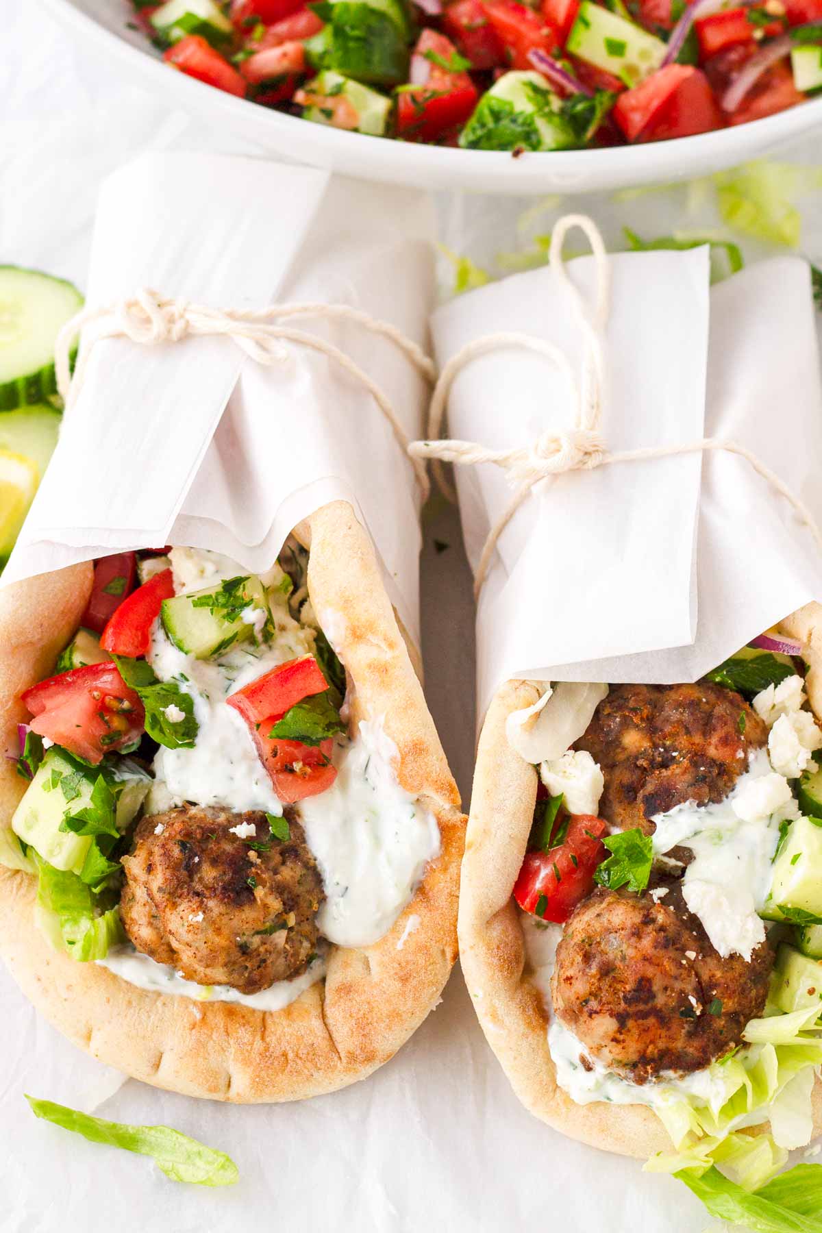 two greek meatball wraps packaged with parchment paper