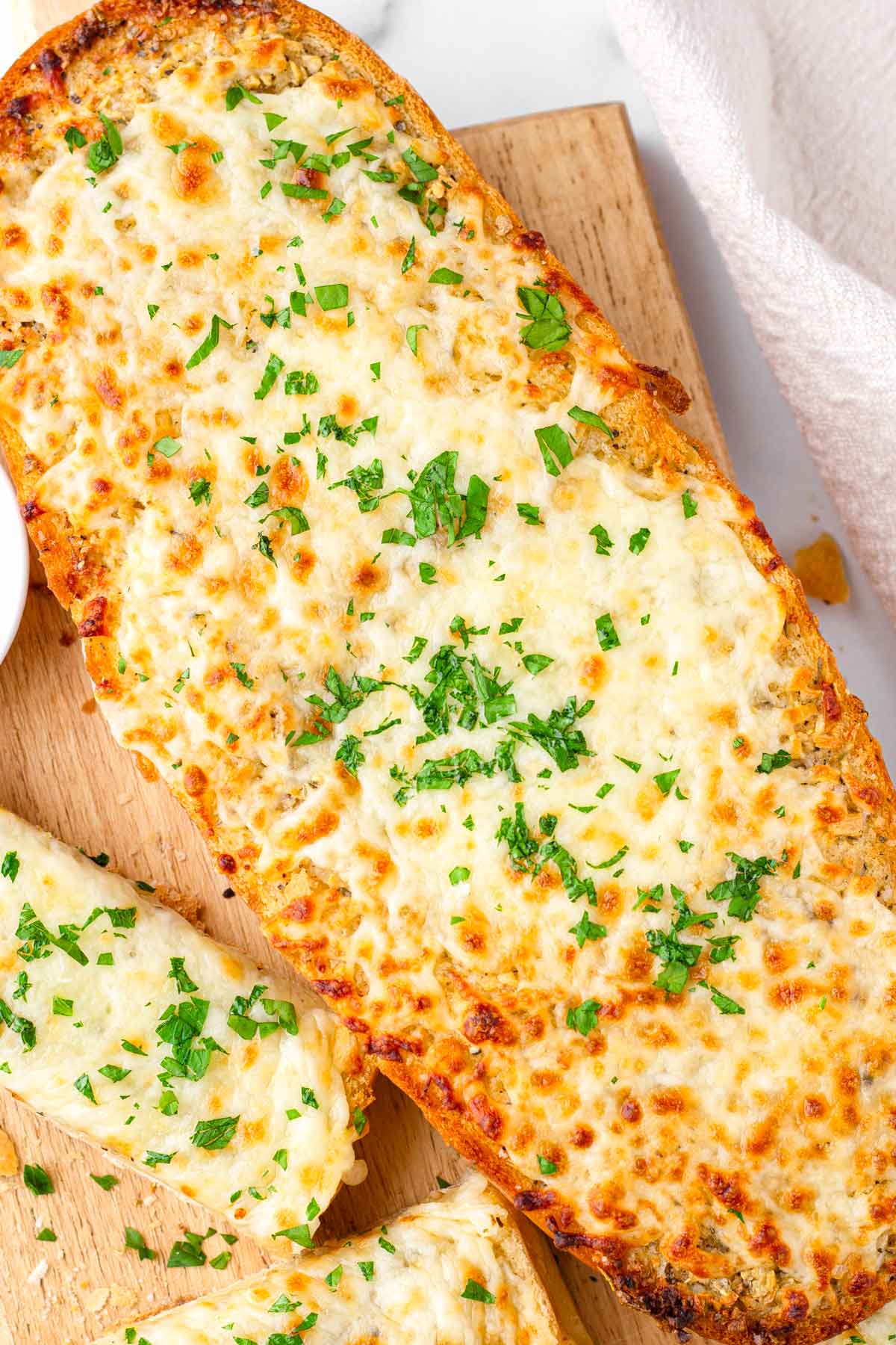baked whole loaf of garlic bread with cheese on a wooden board