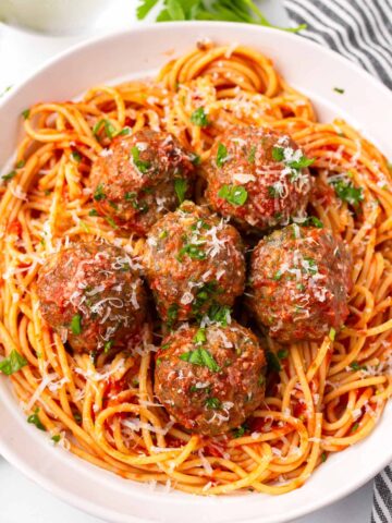 five italian meatballs on red sauce spaghetti