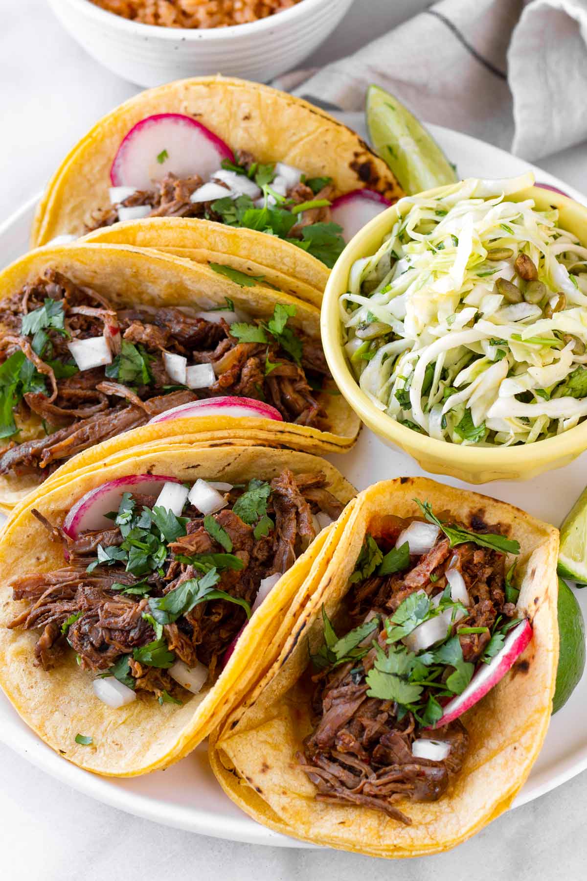 four barbacoa tacos on plate with slaw