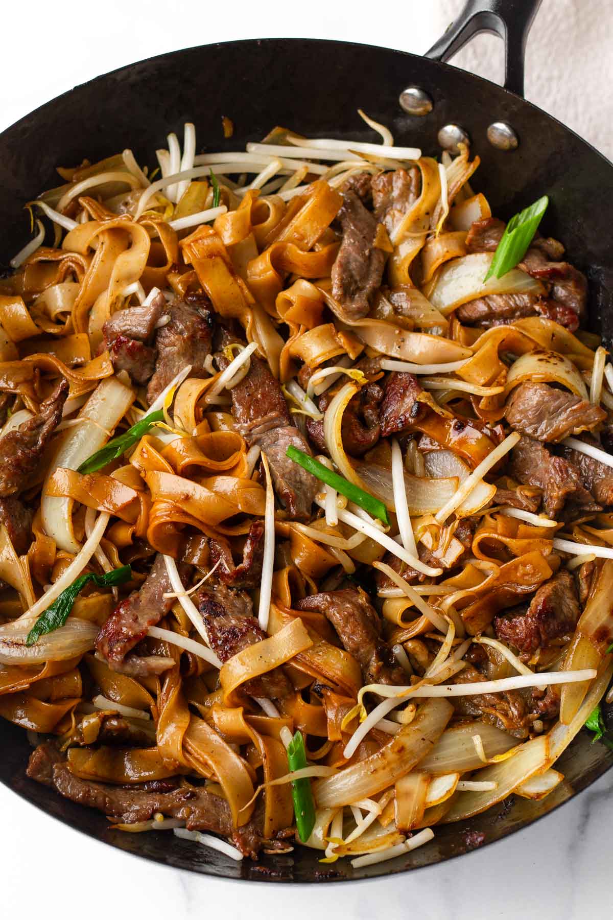 beef chow fun in a wok with garnish