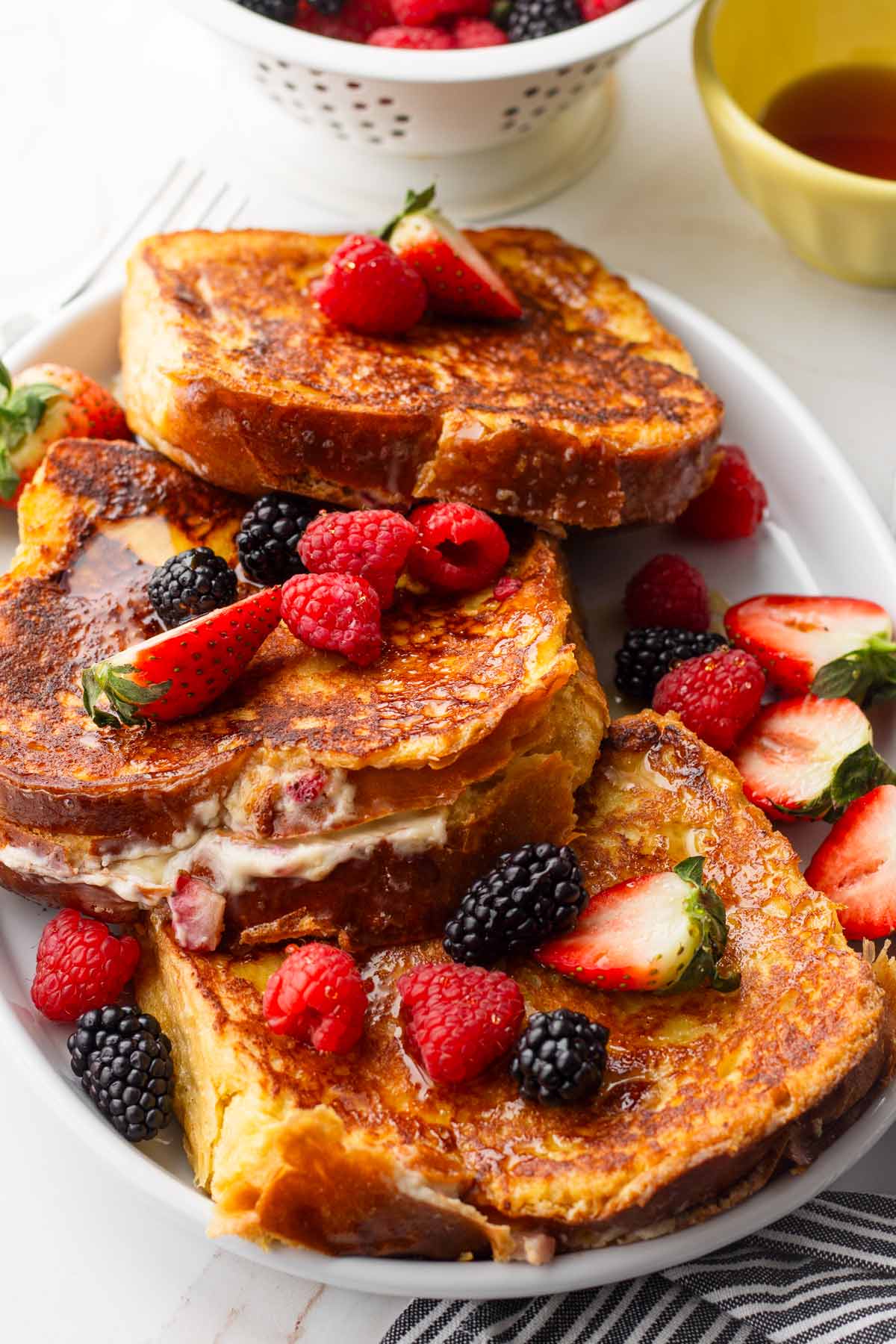 platter with three golden brown french toasts with berries