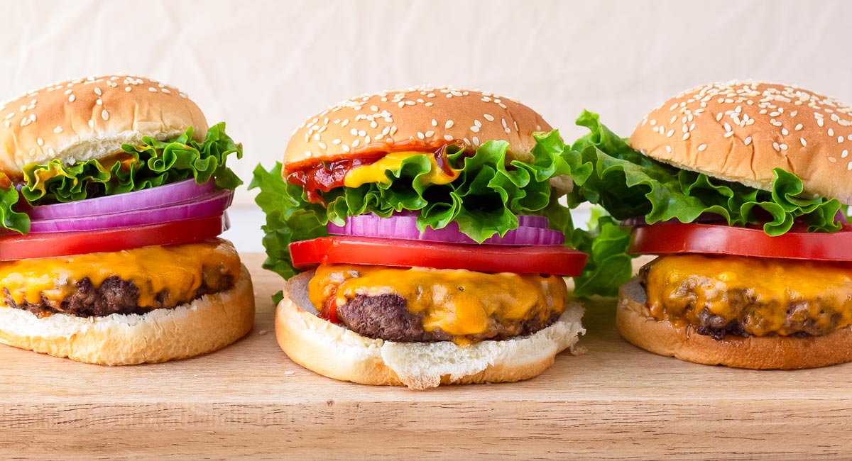 three assembled burgers on wooden board