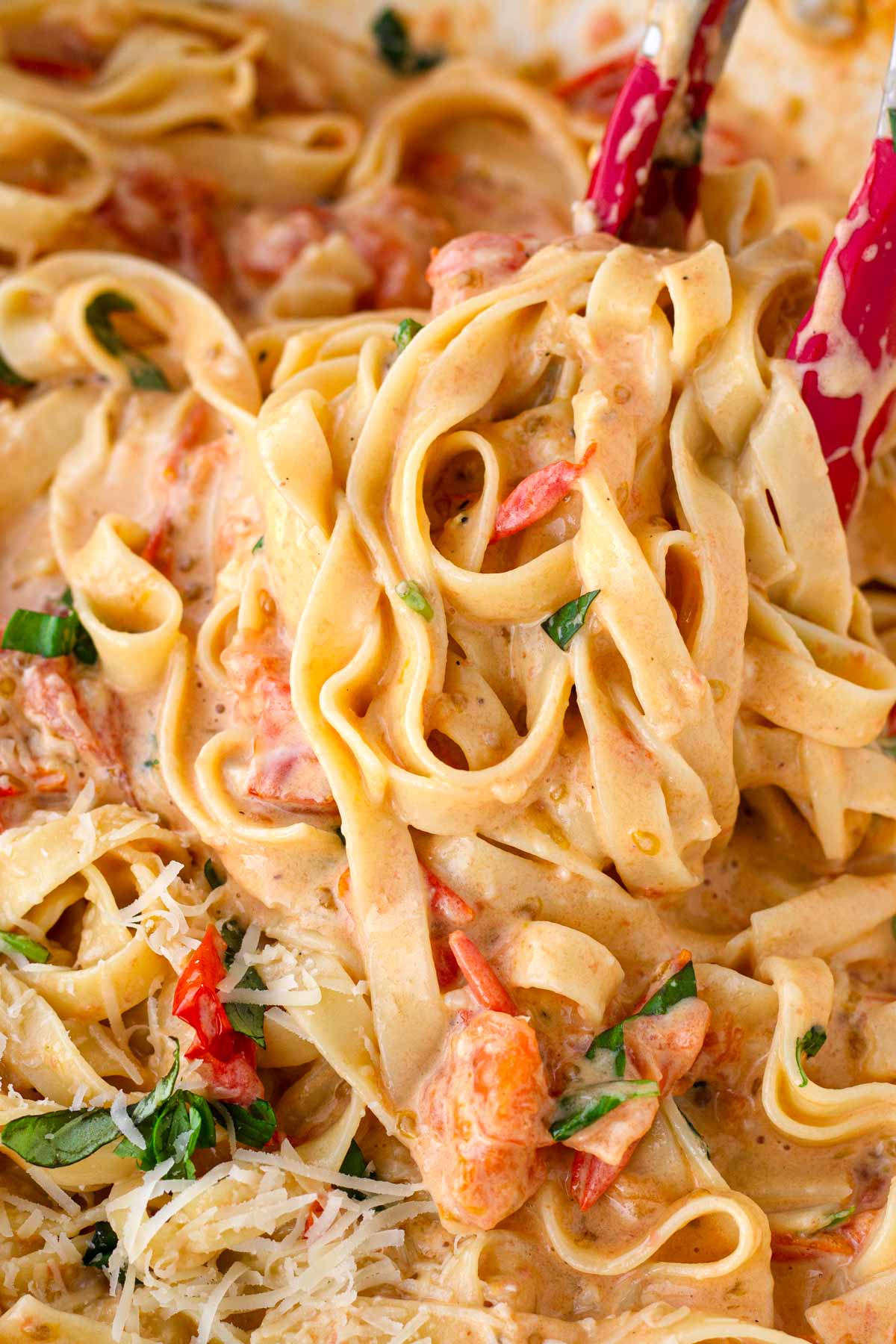 tossing pasta in creamy tomato sauce