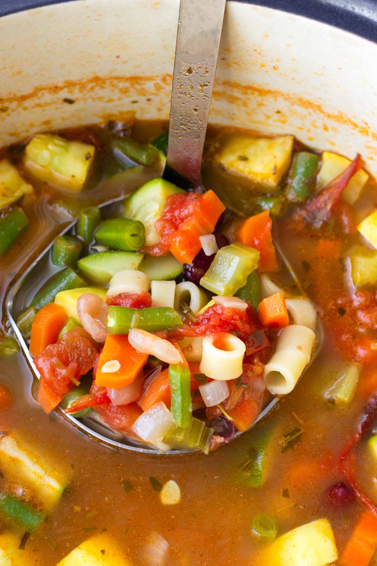 a ladle serving summer minestrone soup