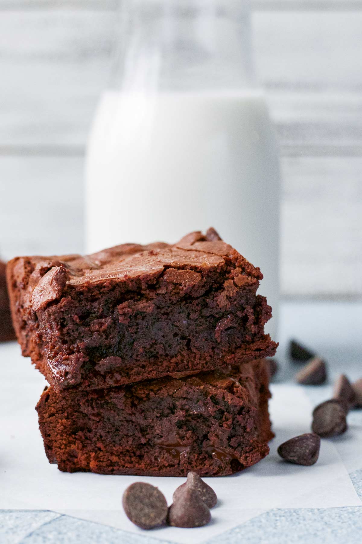 two brownies with a jar of milk behind