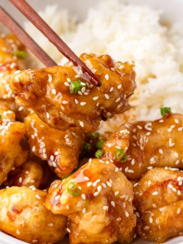 holding a piece of chicken with chopsticks