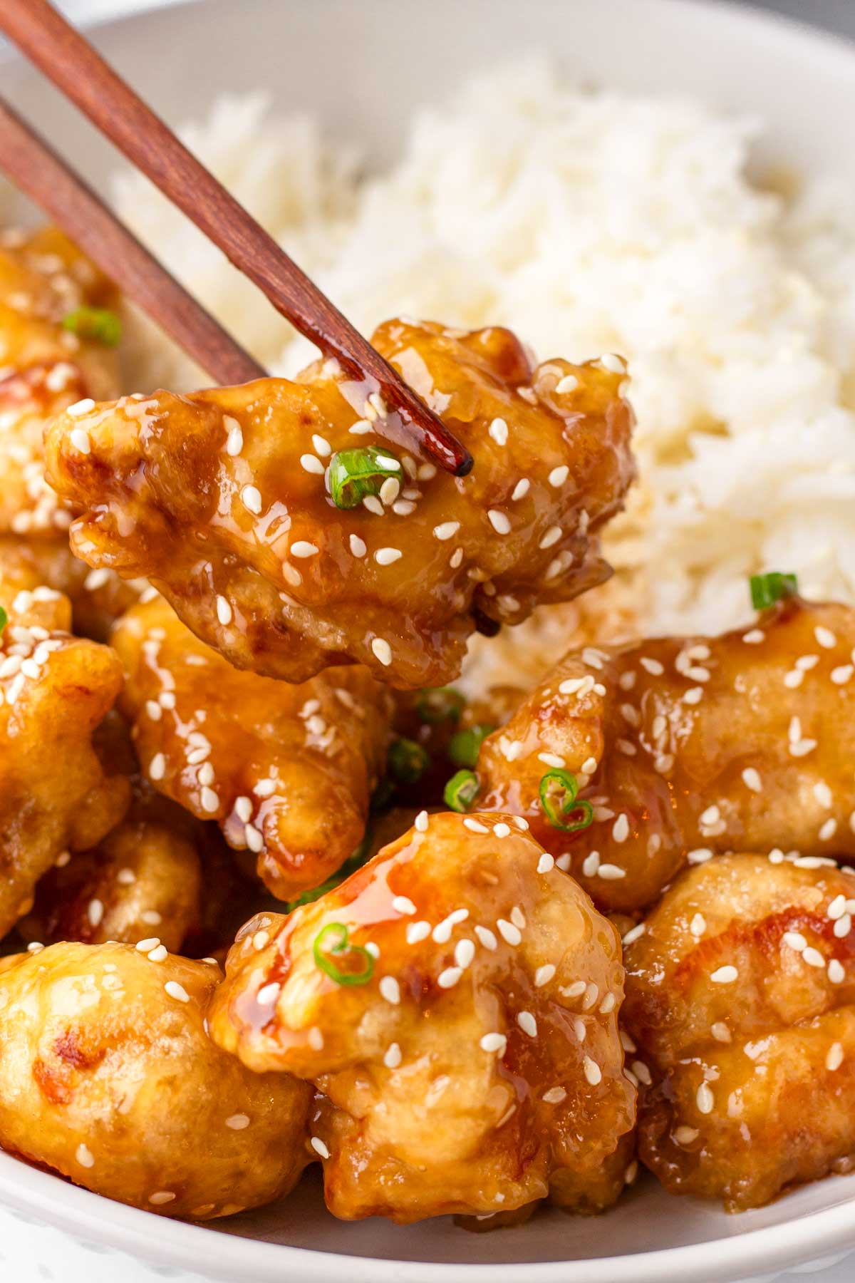 holding a piece of chicken with chopsticks