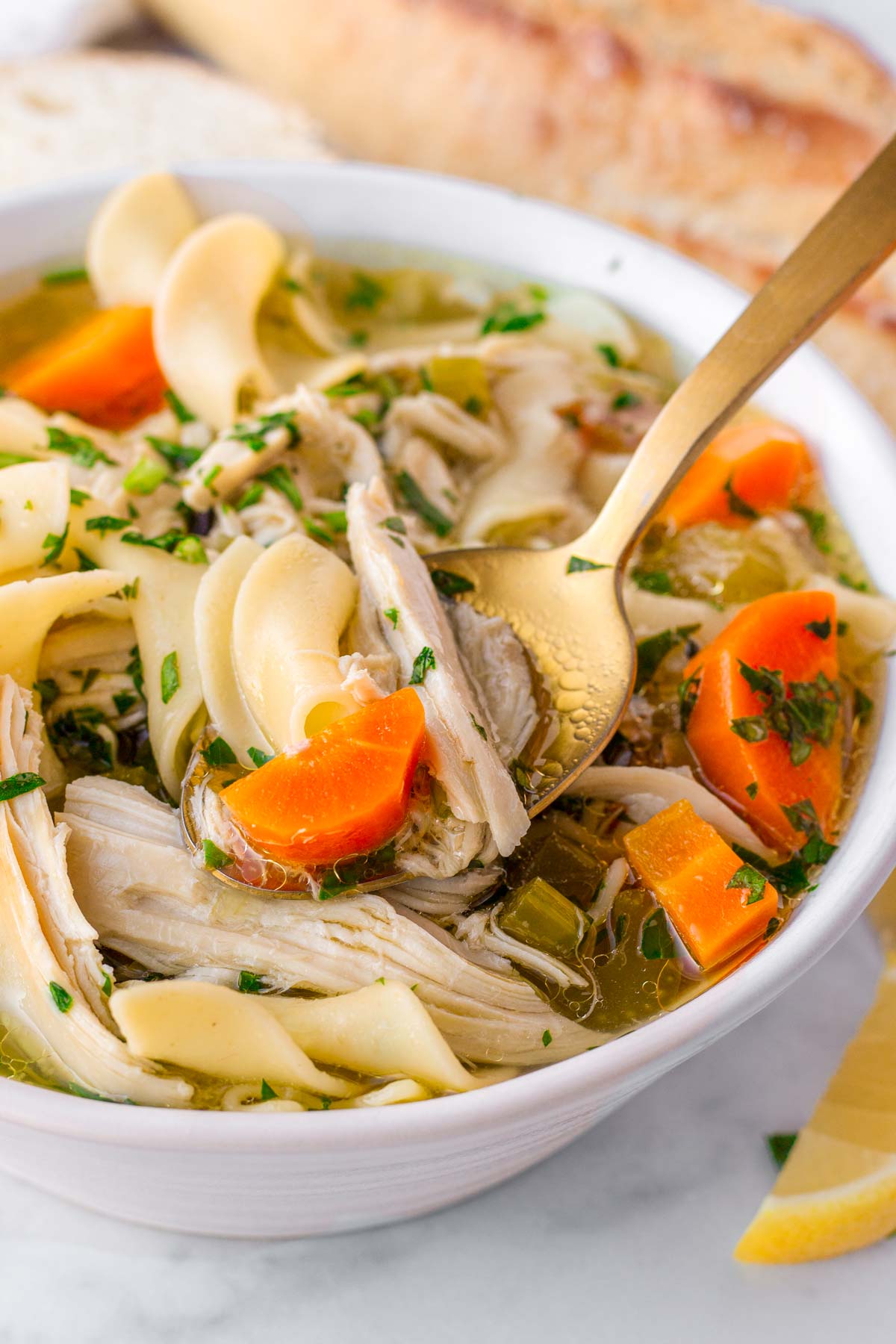 bowl of chicken noodle soup with golden spoon