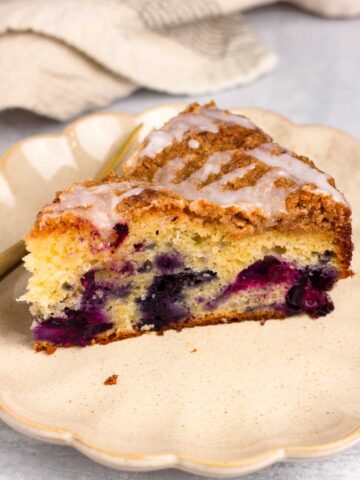 a slice of blueberry coffee cake with streusel and lemon glaze