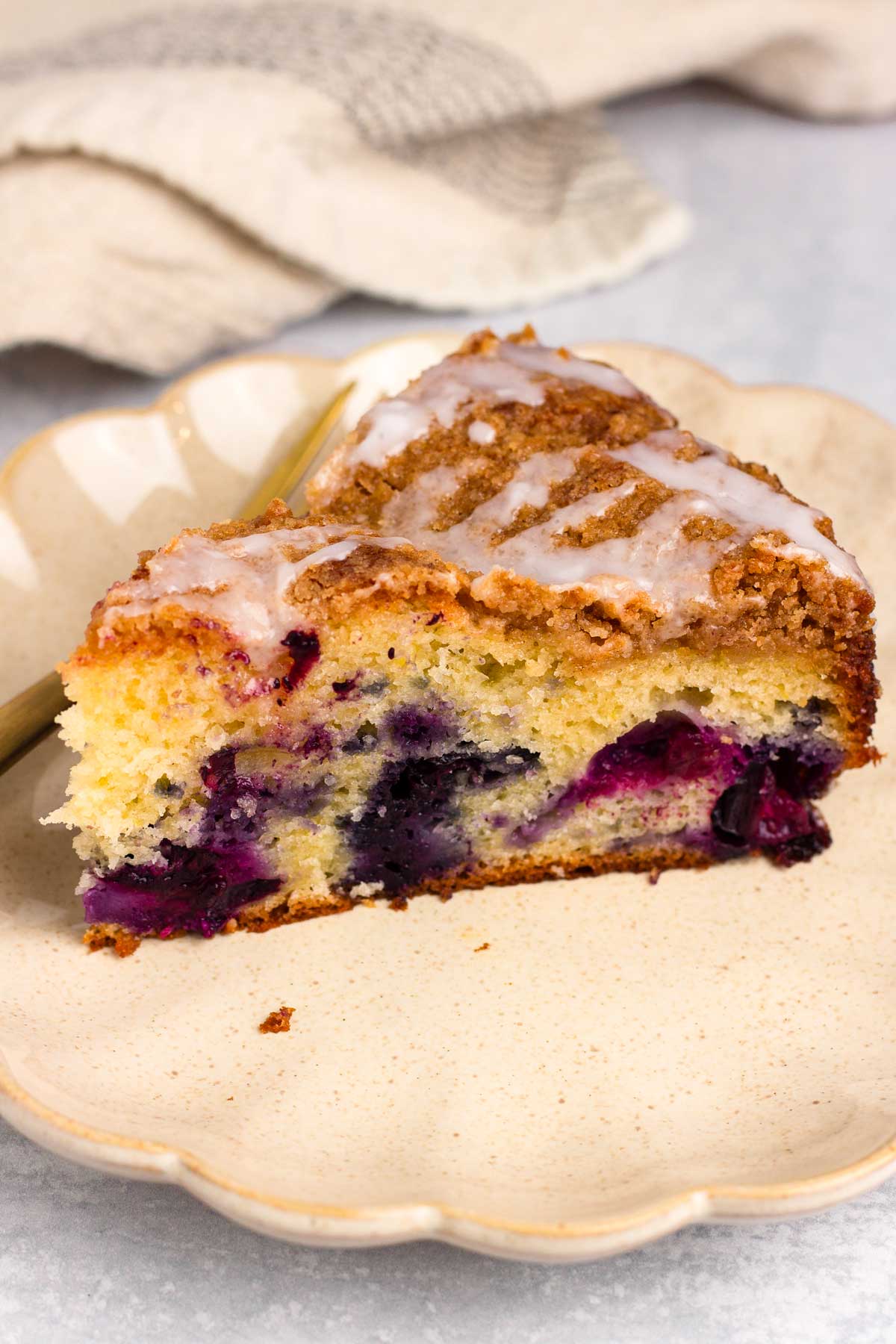 a slice of blueberry coffee cake with streusel and lemon glaze