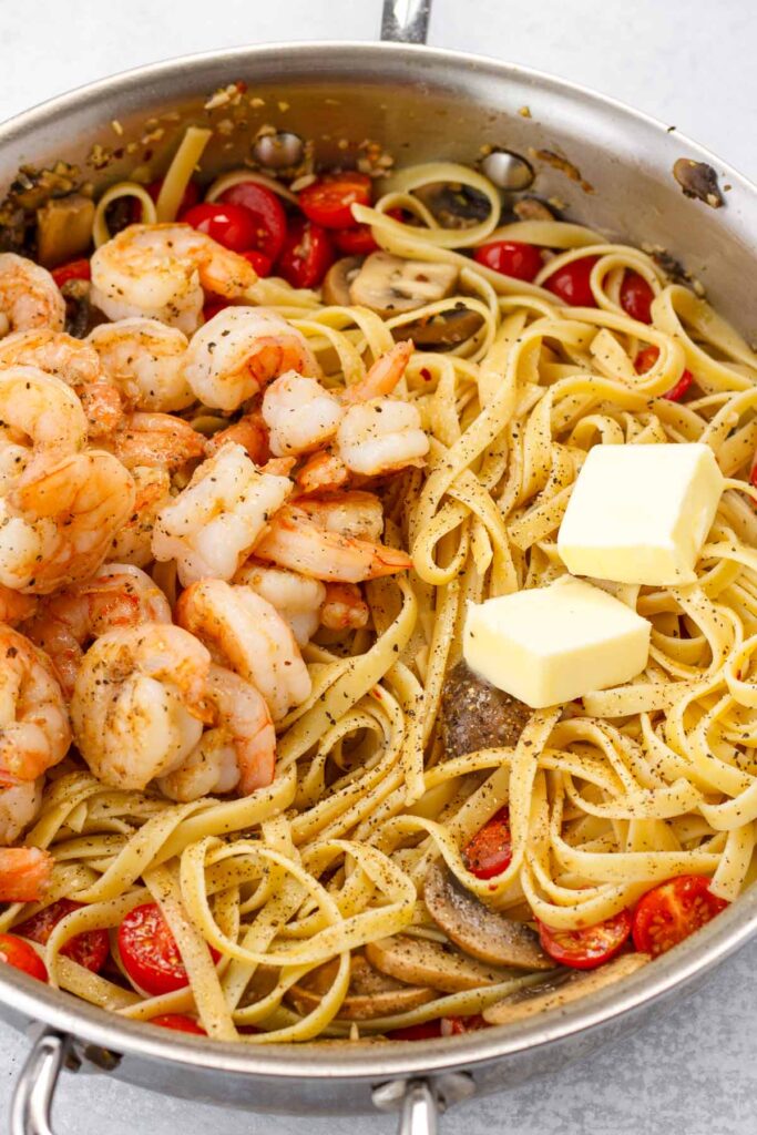 adding shrimp and butter to the pasta