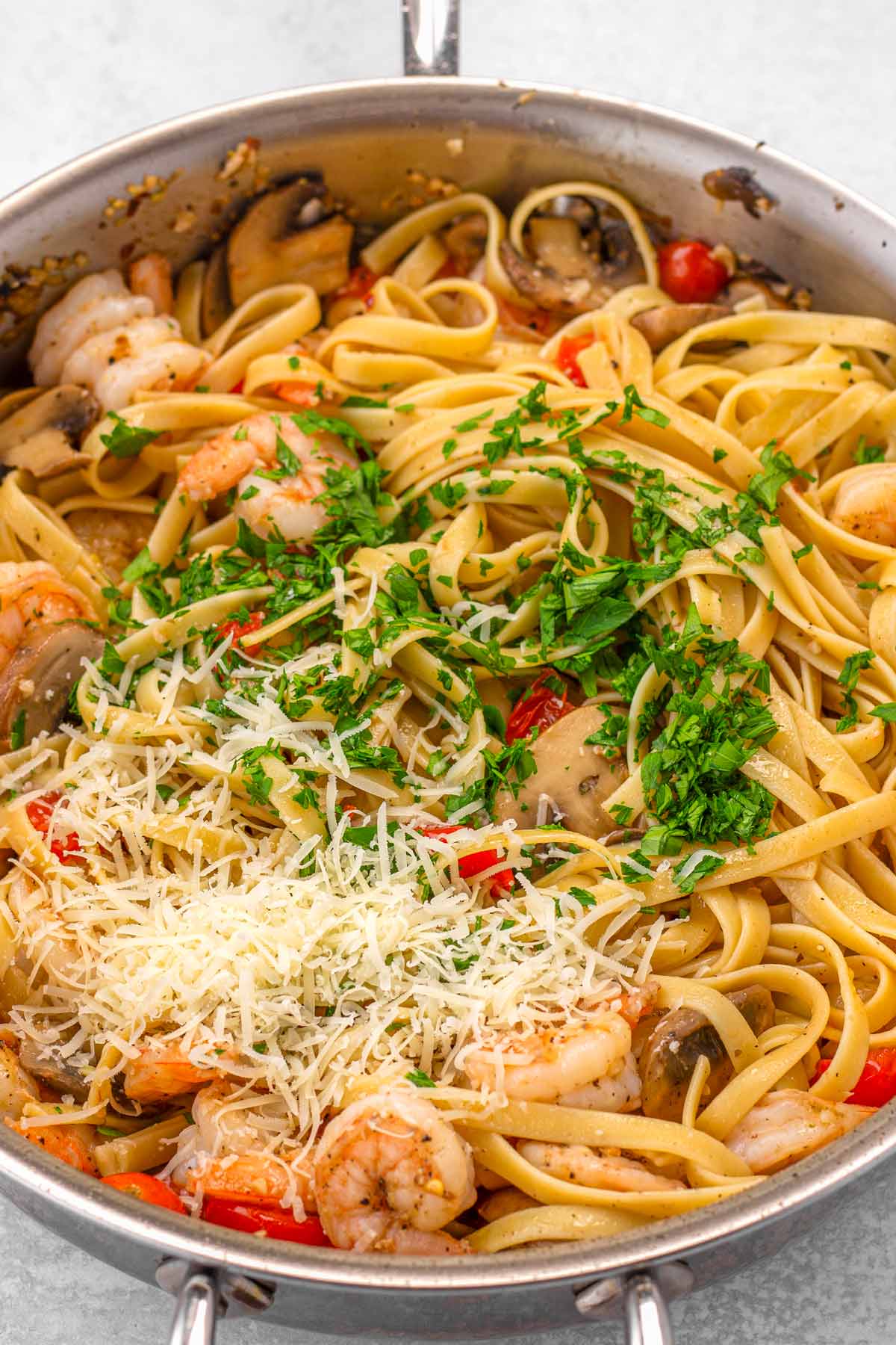 tossing pasta with cheese and parsley