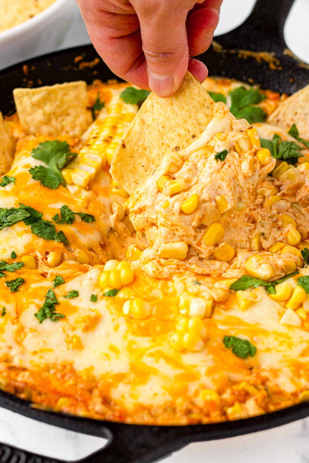 dipping a tortilla chip in the mexican street corn dip