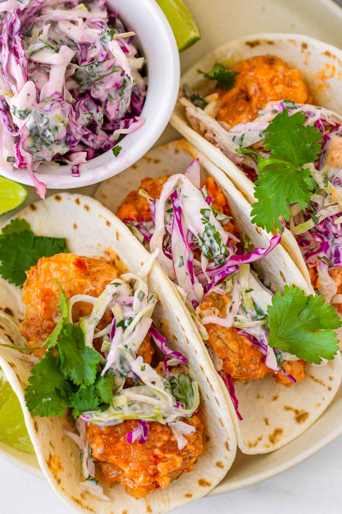 three bang bang shrimp tacos with a side of creamy slaw