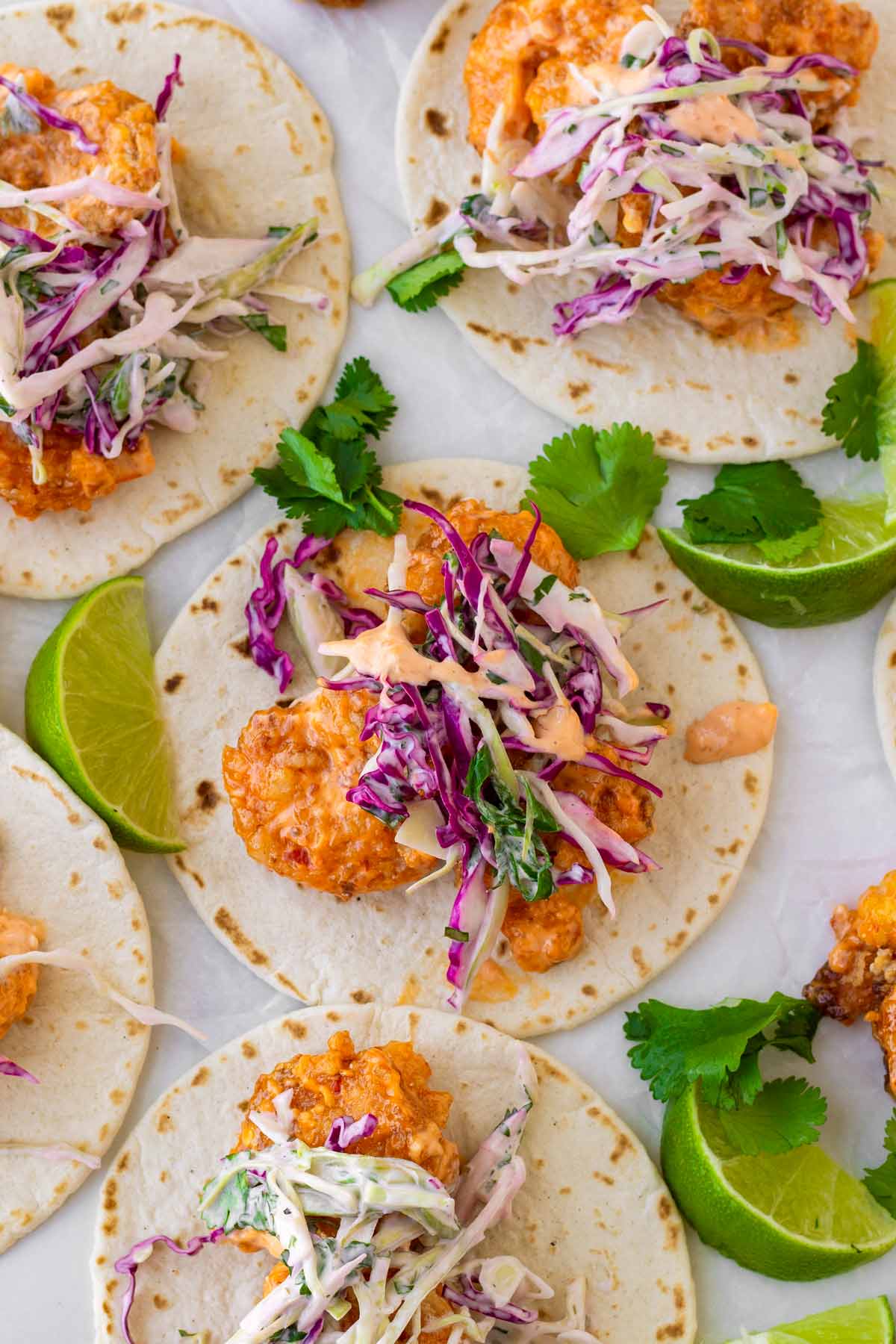 five bang bang shrimp tacos with limes and garnish