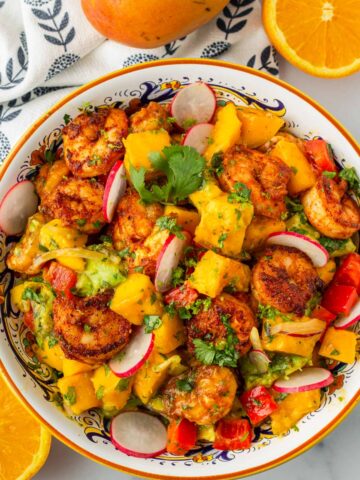 top view of a bowl with mango shrimp salad and fruits