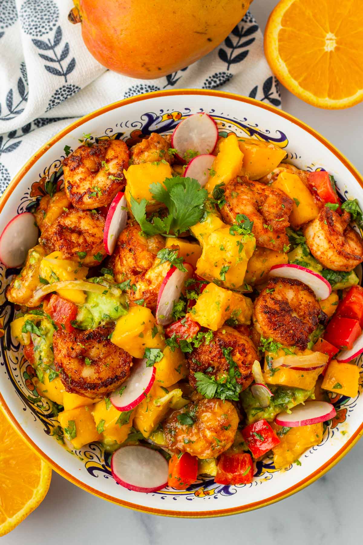 top view of a bowl with mango shrimp salad and fruits