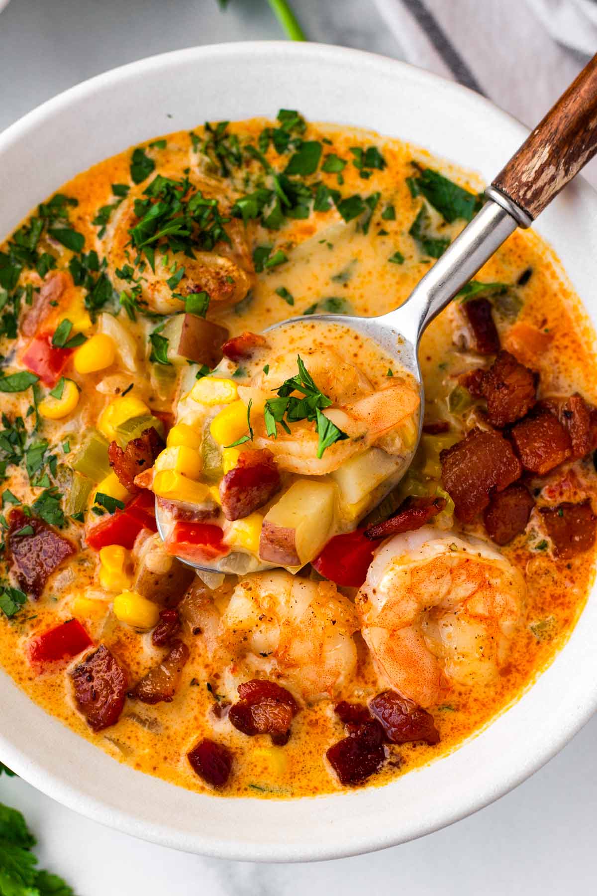 grabbing a spoonful of corn chowder with shrimp and bacon