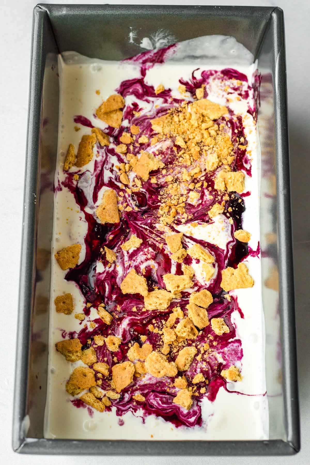 first layer of ice cream, blueberry swirls and crackers in a container