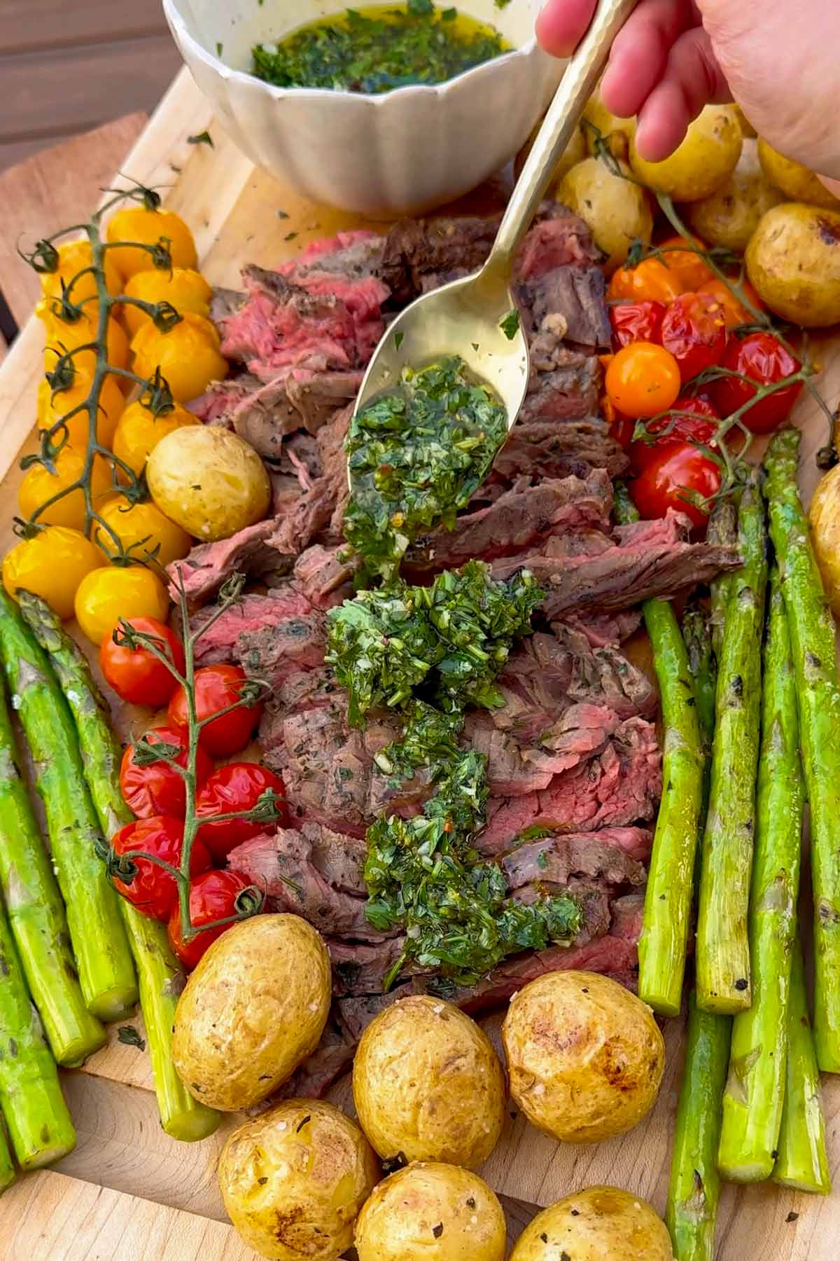 spooning chimichurri sauce over sliced steak