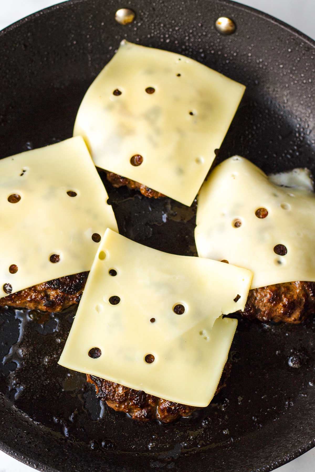 adding cheese on top of the patties