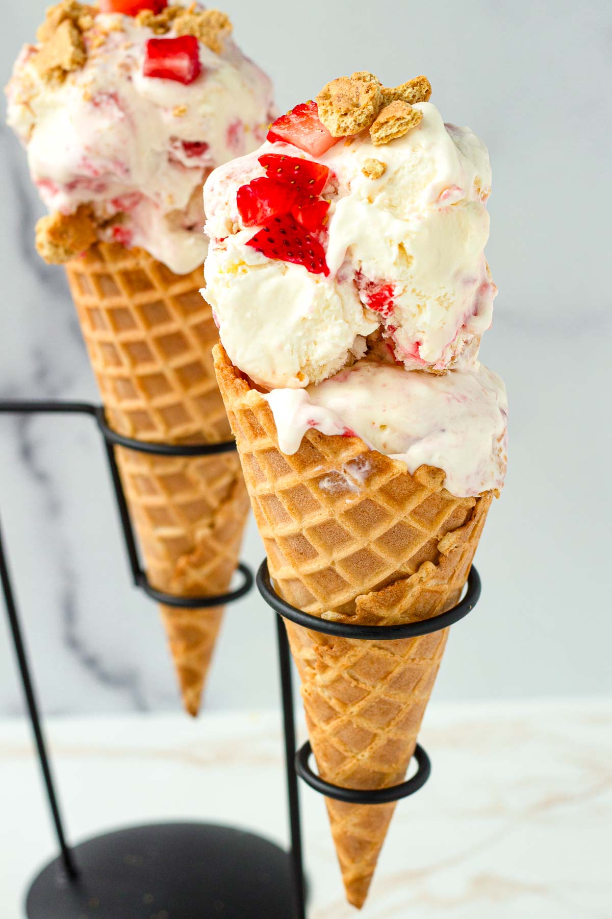 two waffle cones with strawberry cheesecake ice cream