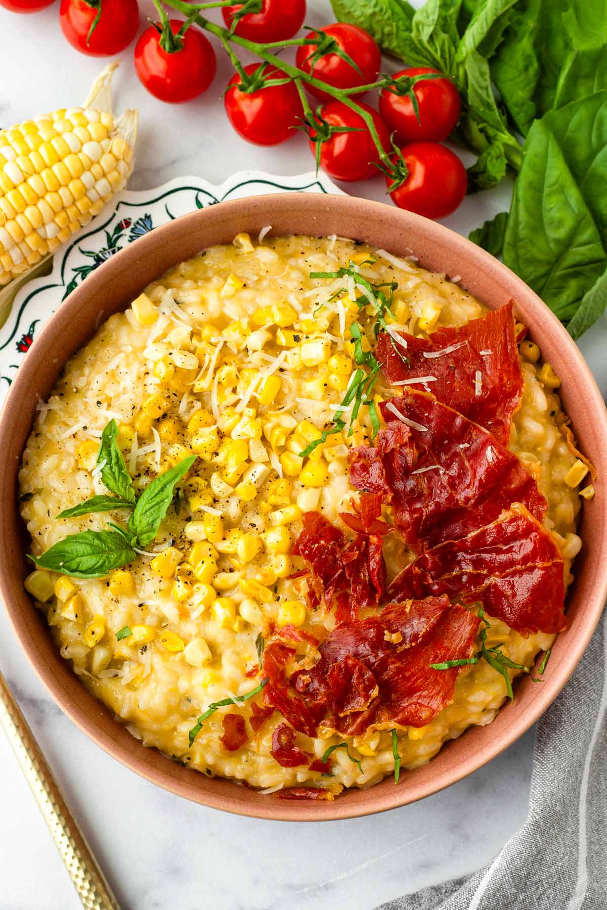 bowl of creamy corn risotto with basil and crispy prosciutto topping