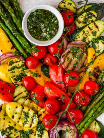 platter with colorful grilled vegetables and a bowl of chimichurri sauce