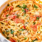 creamy tomato pasta in skillet with garnish