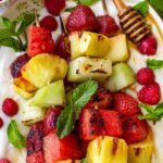 grilled fruit kabobs on yogurt with honey, mint, and raspberries