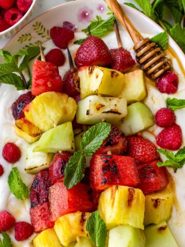 grilled fruit kabobs on yogurt with honey, mint, and raspberries
