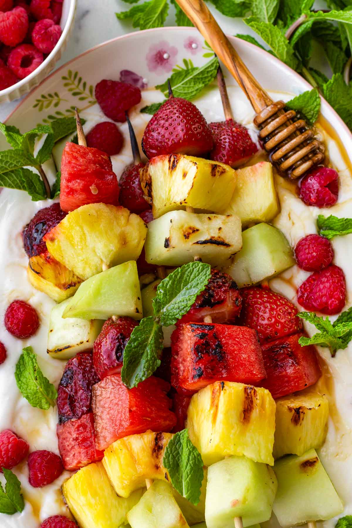 grilled fruit kabobs on yogurt with honey, mint, and raspberries