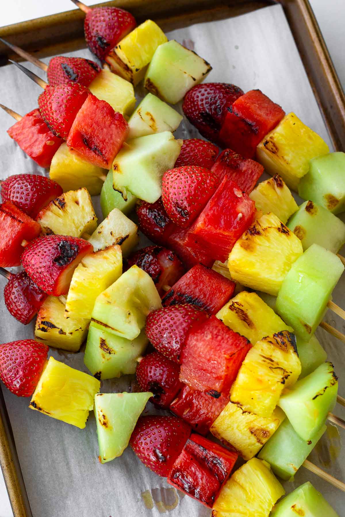 grilled fruit skewers on top of a sheet pan