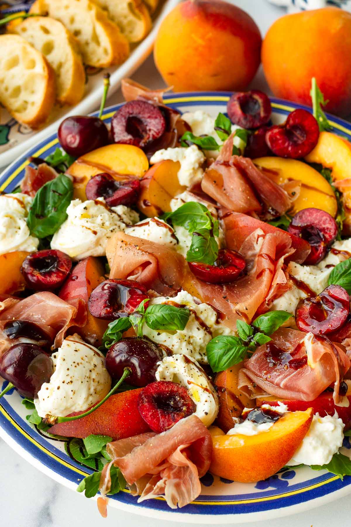 fresh peach burrata salad with red cherries on a platter
