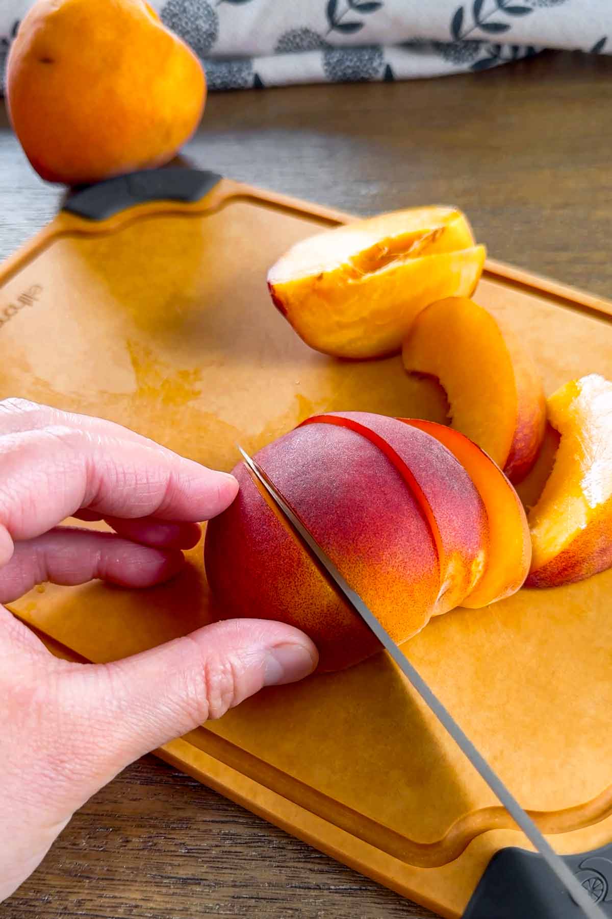 slicing yellow peaches on cutting board