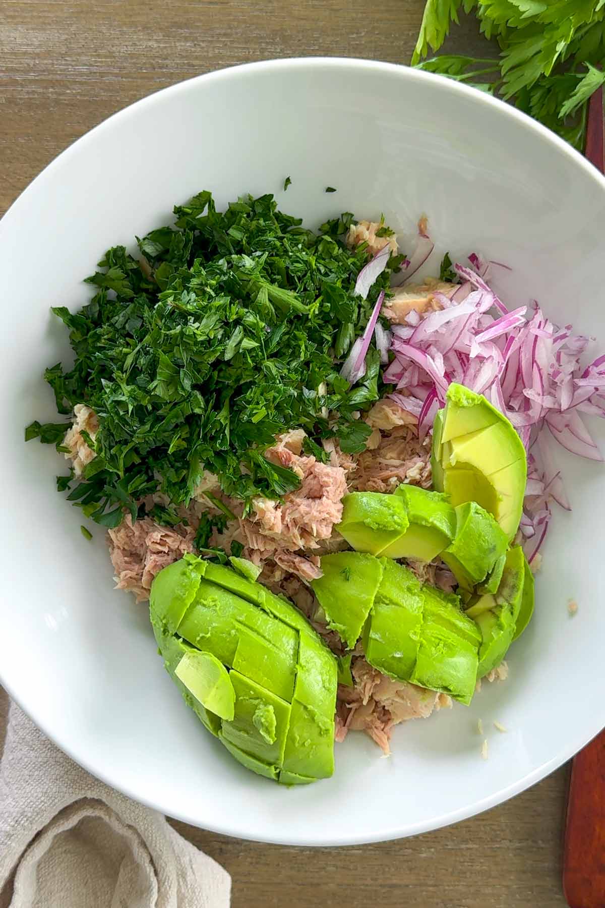 tuna, onions, avoado, and parsley arranged in a bowl