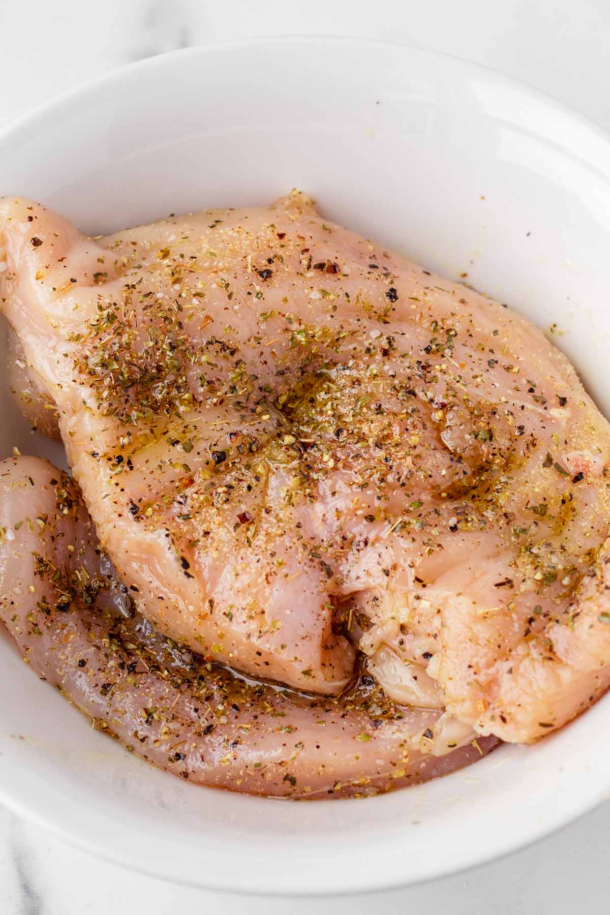 seasoned uncooked chicken breasts in a bowl